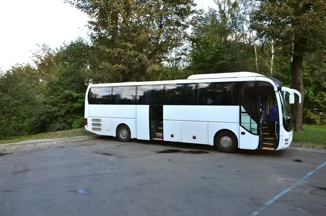 Biały autokar z otwartymi drzwiami czeka na parkingu