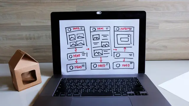 Laptop ze szkicem ekranów aplikacji na jasnym biurku